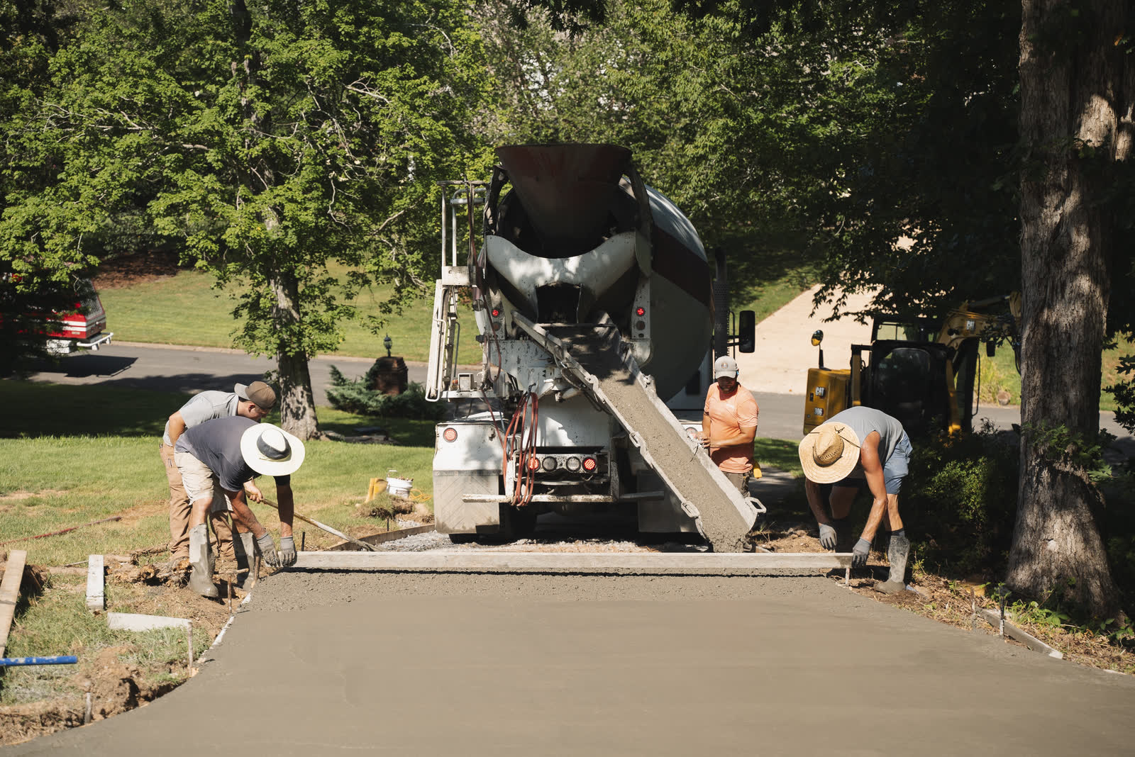Concrete mixer truck pouring a new driveway while the Platinum Development crew screeds the fresh slab in Chattanooga, TN