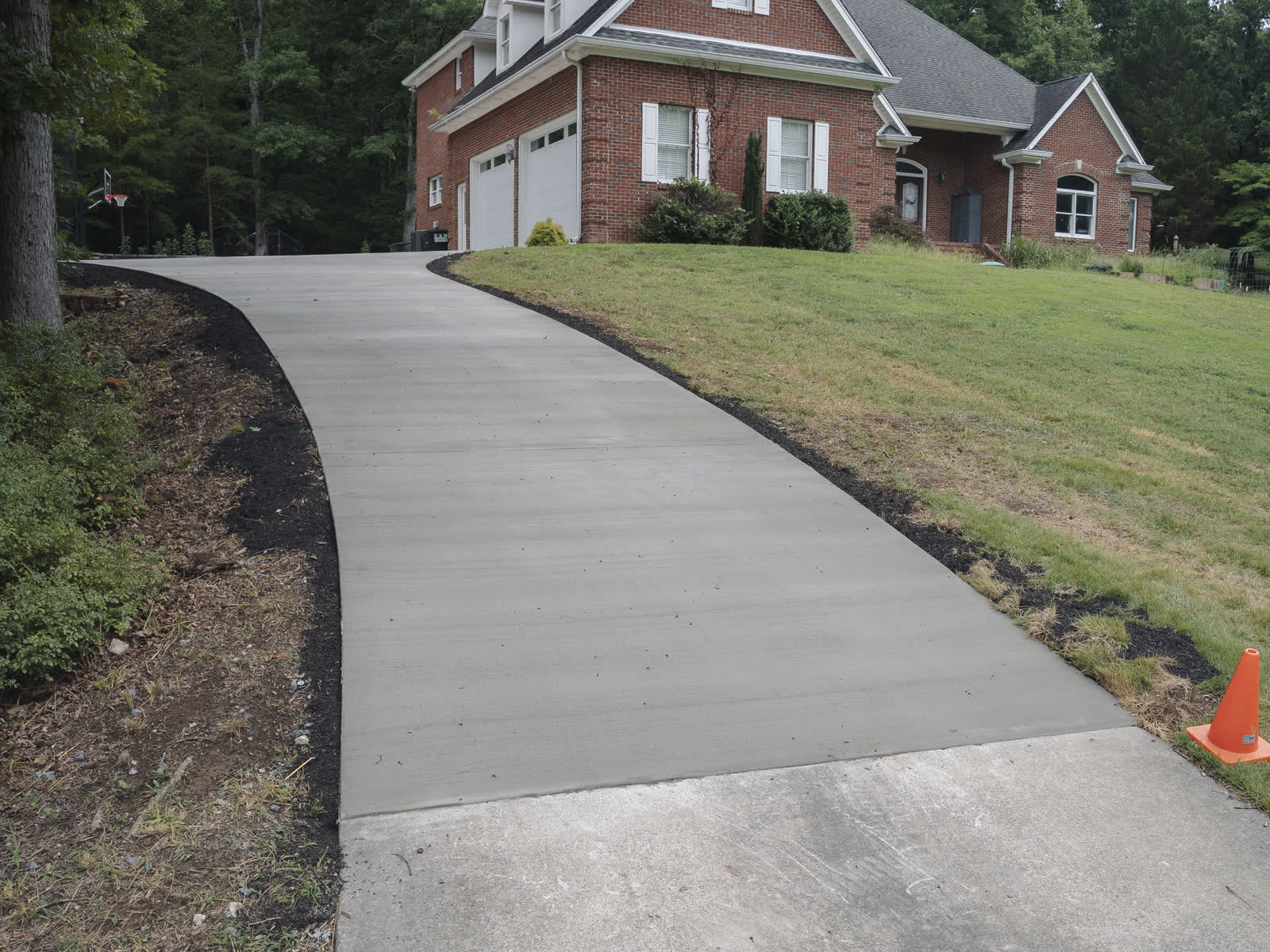 Finished concrete driveway sweeping from the garage down to the road at a brick home in Chattanooga, TN